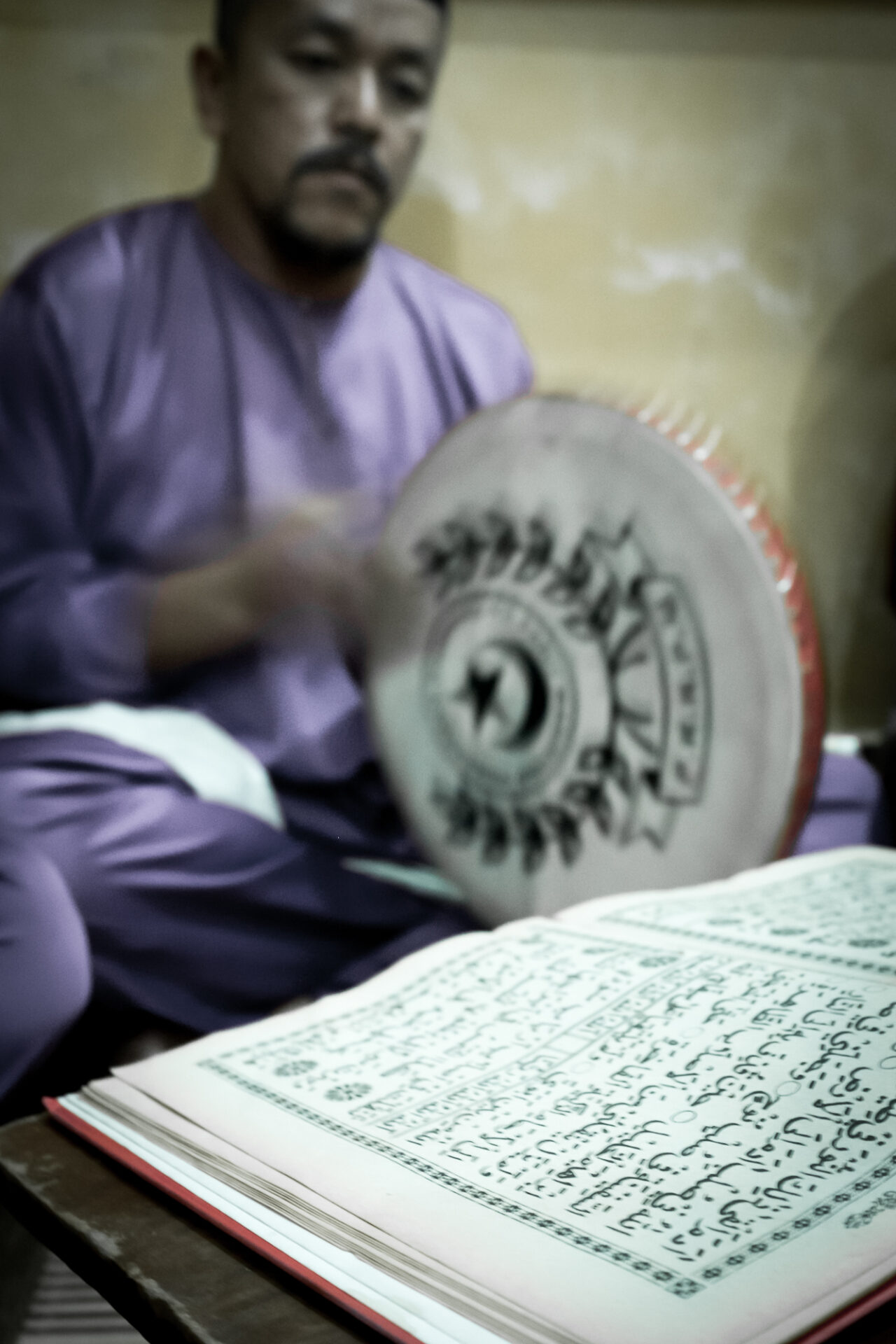 A man paying drum while looking at the book, Kompang Jidor