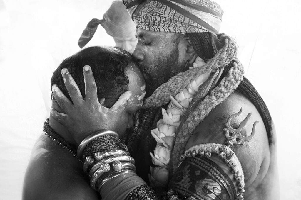 A hindu religious person kissing another person on forehead